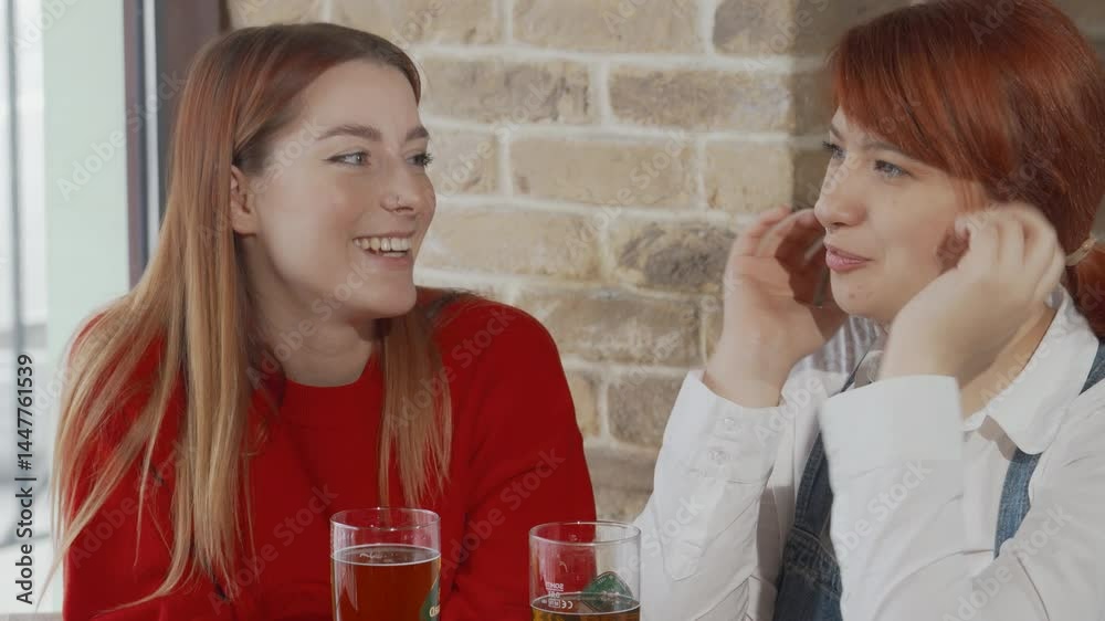 Joyful female friends enjoying drinks at a lively beer pub Joyful female friends enjoying drinks at a lively beer pub