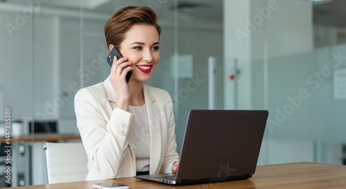 Woman in office using laptop and talking on phone smiling business.