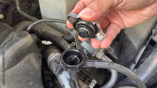 Hand of car auto mechanic engine, technician service check coolant cooling fluid water, he open radiator cap for change or repair the in garage. Check car radiator, car maintenance 