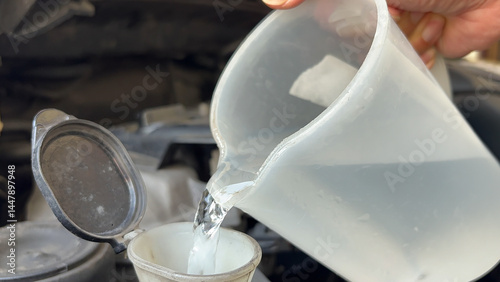 Pouring antifreeze Filling a windshield washer tank with an antifreeze. Pouring liquid into car washer tank to clean the windshield. hands pour water from bottle