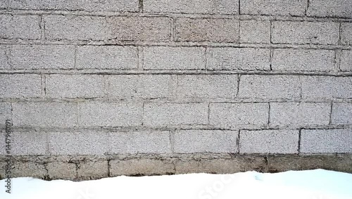 Snowy Winter Scene Featuring a Textured Concrete Wall with Subtle Architectural Details