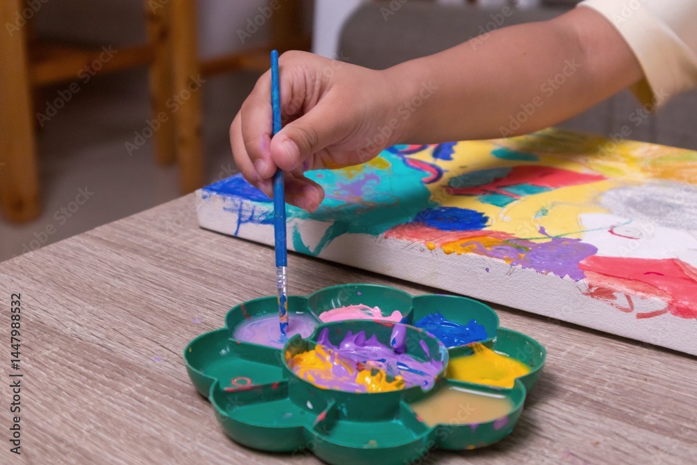 Close up view of little girl's hand mixing watercolors on a watercolor palette Close up view of little girl's hand mixing watercolors on a watercolor palette