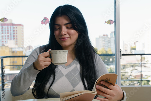 young Venezuelan woman at home drinking coffee and having breakfast