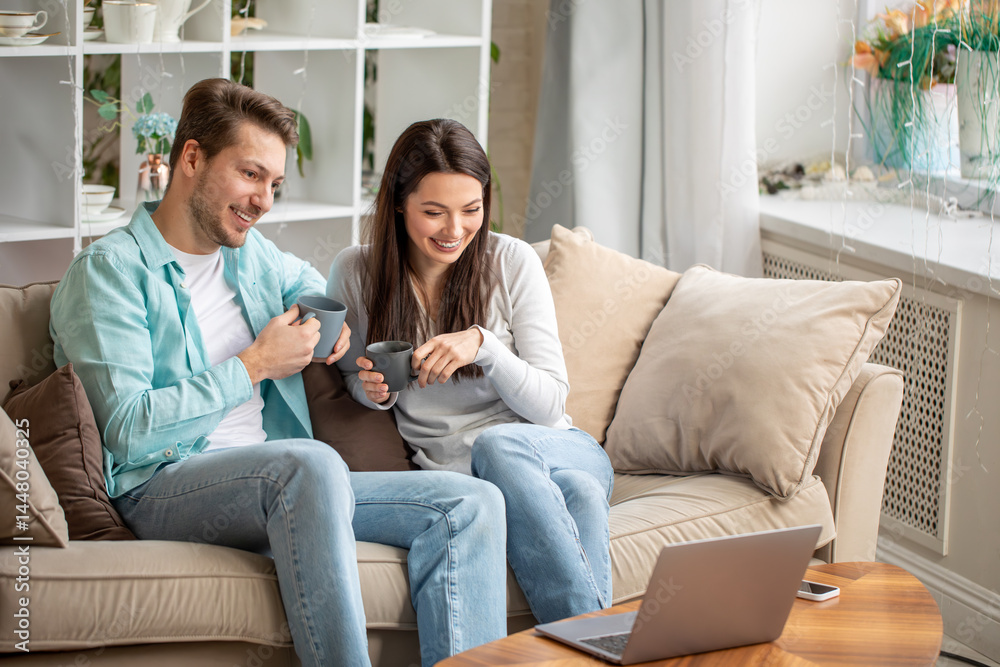Couple enjoying tea time while watching laptop Couple enjoying tea time while watching laptop