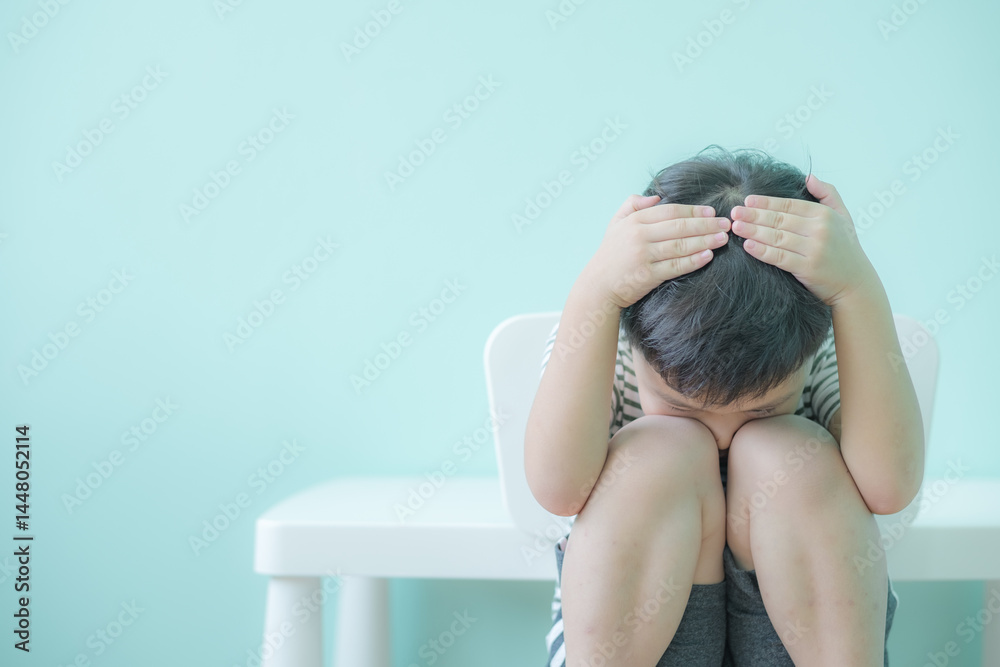Fototapeta premium Lonely boy sitting alone. Preschool child with unhappy or sad face. Copy space for text.