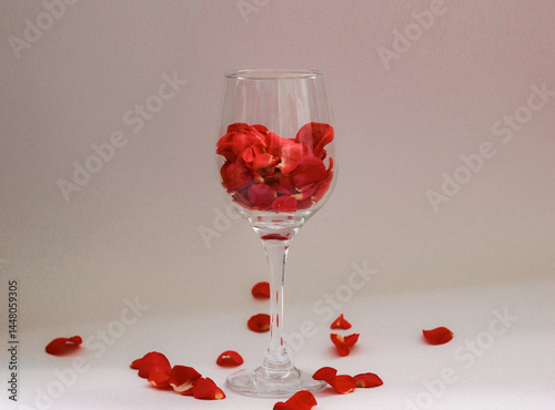 Romantic still life with red rose petals in a wine glass on soft pink background. Perfect for Valentine’s Day, love-themed content, or elegant floral compositions.