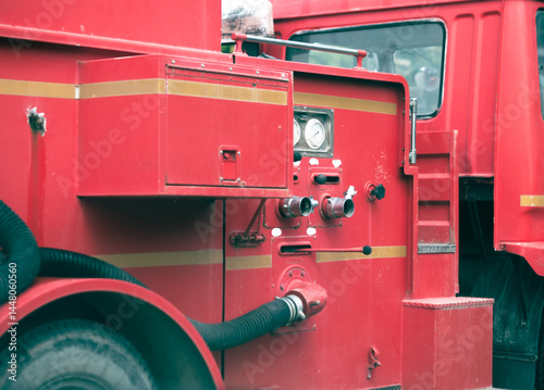 This image shows the side control panel of a red fire truck. It features pressure gauges, control valves, and water connection pipes, which are used to control the water spray system during firefighti