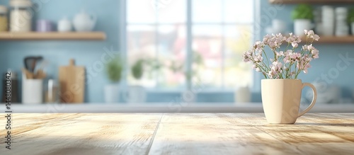 White mug with baby's-breath flowers on wooden table in blue-walled kitchen with shelves and window.