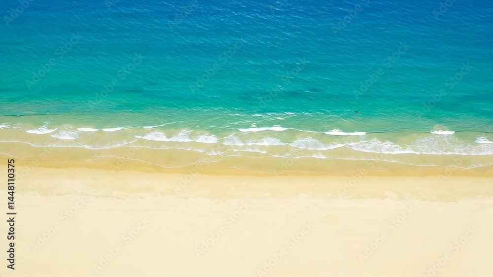 Aerial view of coastline with blue water and sandy beach, waves gently rolling onto shore Aerial view of coastline with blue water and sandy beach, waves gently rolling onto shore