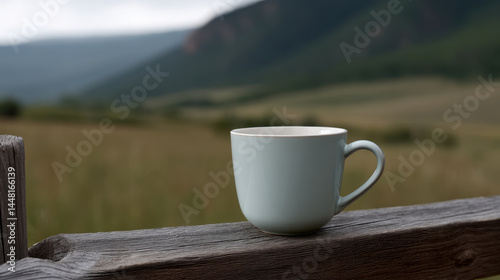 Lone coffee cup sits on wooden fence post with mountain view