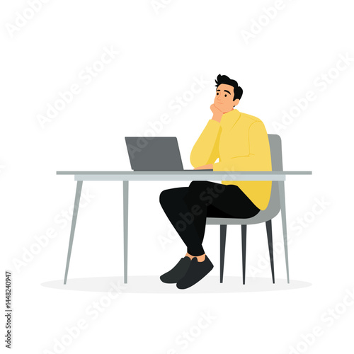 Pensive man sitting at a desk with a laptop in a modern workspace