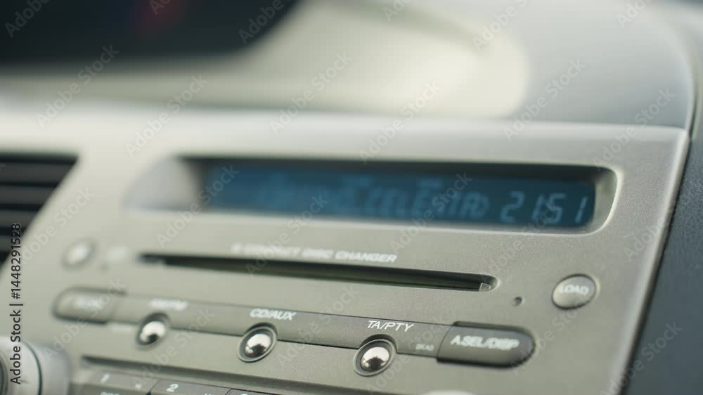 close up of car dashboard displaying built-in cd player with labeled control buttons and digital screen showing music information inside vehicle interior during daylight close up of car dashboard displaying built-in cd player with labeled control buttons and digital screen showing music information inside vehicle interior during daylight