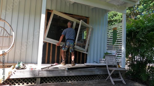 Carpenter removes wooden window from cottage