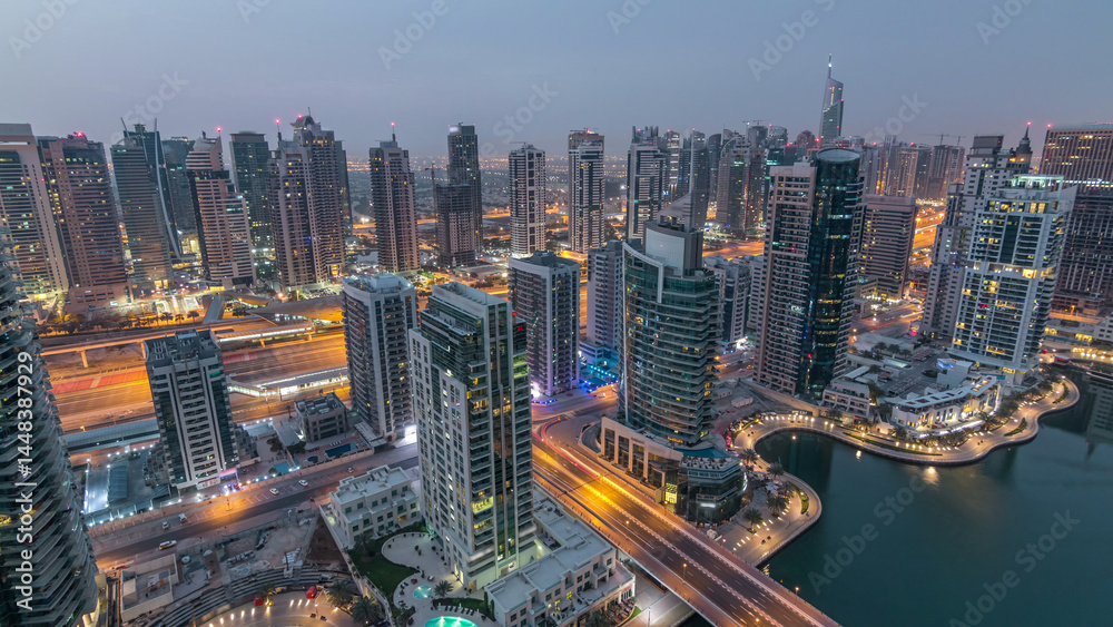 Fototapeta Aerial top view of Dubai Marina night to day timelapse. Modern towers and traffic on the road