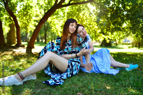 The daughter-in-law and mother-in-law relaxing on the green grass against the backdrop of trees in the park