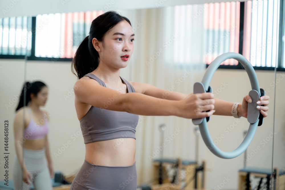 Obraz premium Young Asian Woman Doing Pilates Exercises with Magic Circle in Gym