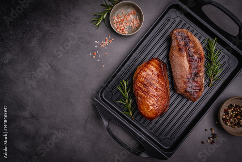 Roasted or grilled duck breast with the addition of aromatic herbs on a grill pan, top view. Food recipe background. Close up. High quality photo