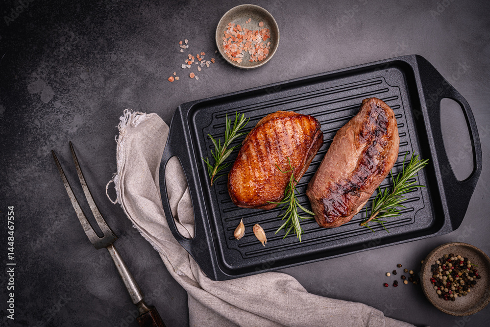 Roasted or grilled duck breast with the addition of aromatic herbs on a grill pan, top view. Food recipe background. Close up. High quality photo