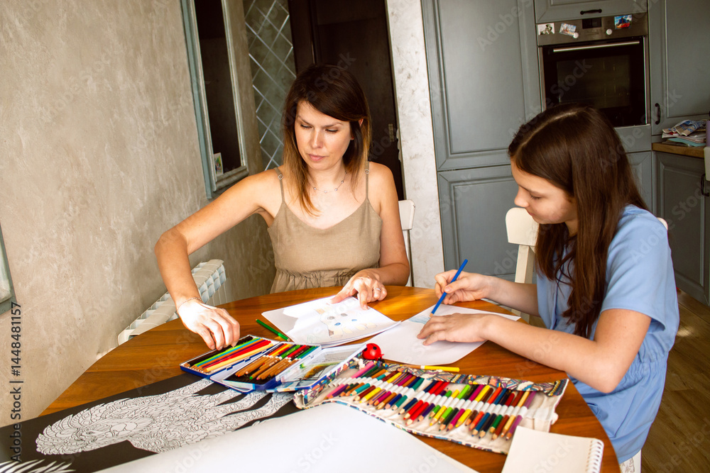 Fototapeta premium Mother and daughter laughing while drawing together, sharing tender moment. Touching scene of carefree childhood and qualitative parental involvement.