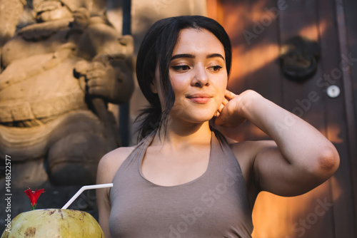Obraz na płótnie Positive caucasian female recreating outdoors holding cocos for drinking and refresh with organic food, smiling young woman relaxing and concentrated on recreating on healthy lifestyle w salonie