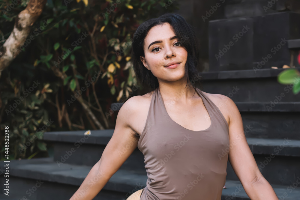 Young calm woman doing yoga and meditating on stairs