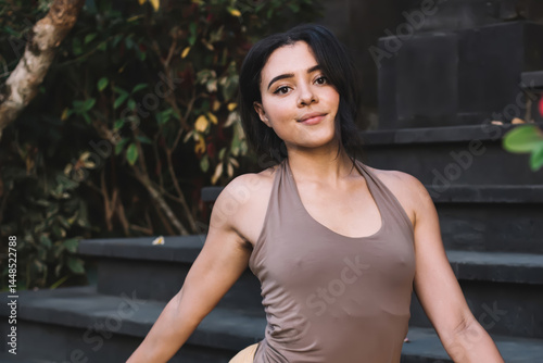 Young calm woman doing yoga and meditating on stairs