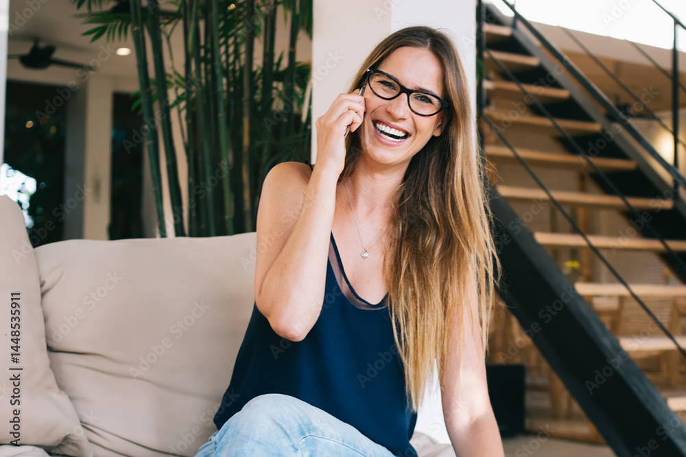 Cheerful woman talking on smartphone in cafe