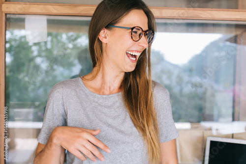 Obraz na płótnie Beautiful female in gray T shirt laughing in modern workspace w salonie