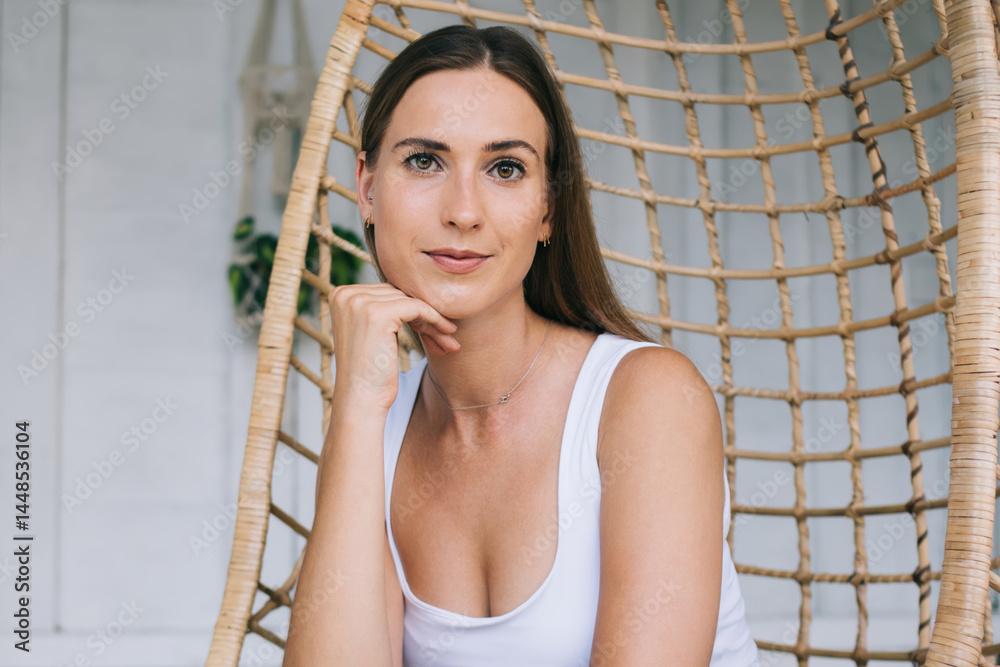 Thoughtful young lady sitting in comfortable wicker chair
