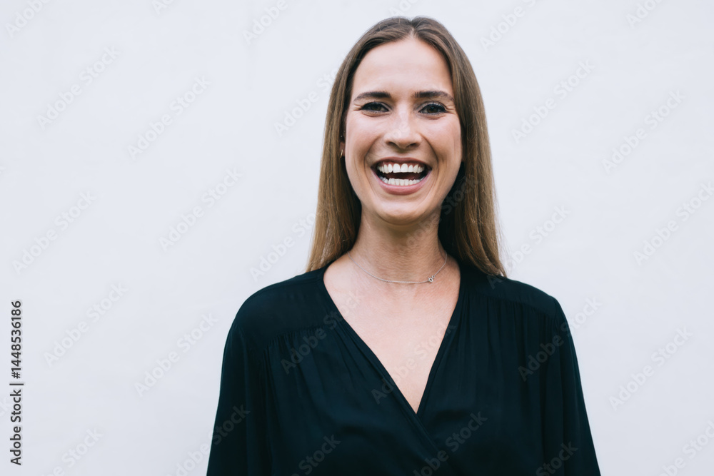 Young model in black dress looking at camera and laughing