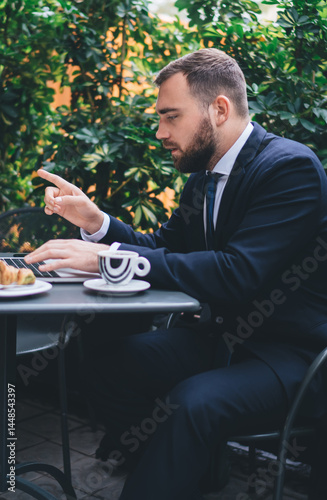 Obraz na płótnie Pensive guy using laptop while sitting in garden cafe w salonie