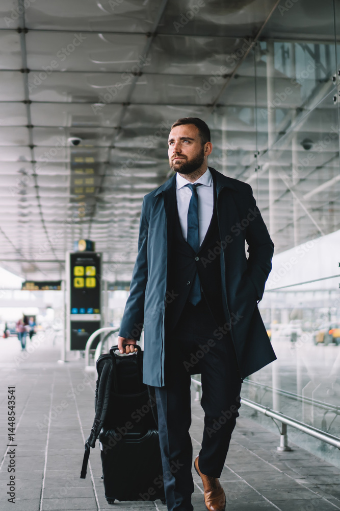 Elegant passenger with luggage walking near airport building