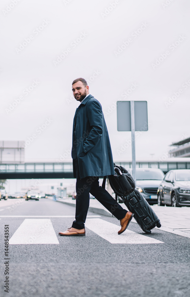 Businessman with suitcase crossing road to airport