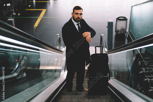 Obraz na płótnie Serious businessman riding on moving stairs in airport w salonie