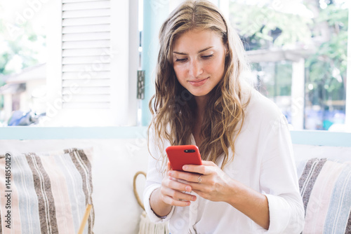 Obraz na płótnie Joyful woman using smartphone while having breakfast at home w salonie
