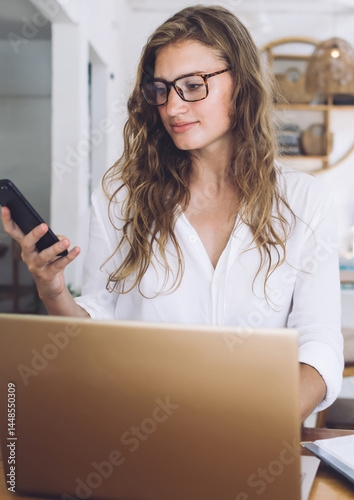 Obraz na płótnie Freelancer using phone while working at laptop in cafe w salonie