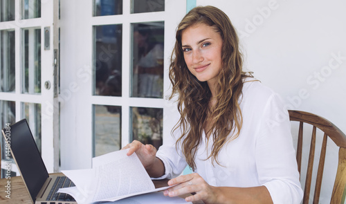 Obraz na płótnie Joyful young female student scrolling through book and sitting a w salonie