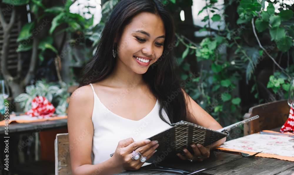 Cheerful woman reading menu in outdoor cafe