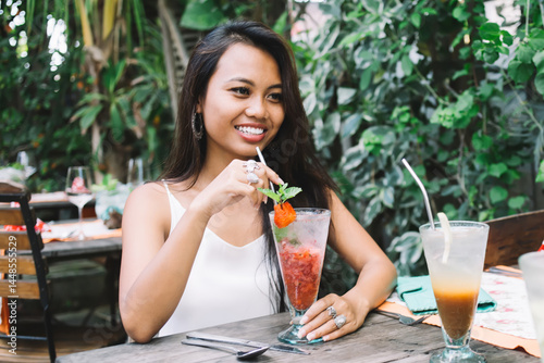 Cheerful women drinking cocktail and talking in outdoor cafe