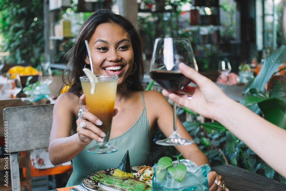 Females smiling and clinking drinks in exotic outdoor restaurant
