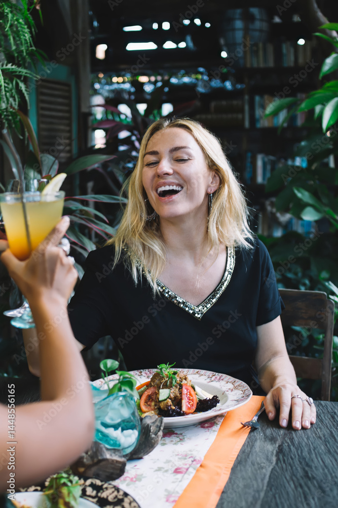 Two diverse females clinking glasses in exotic restaurant
