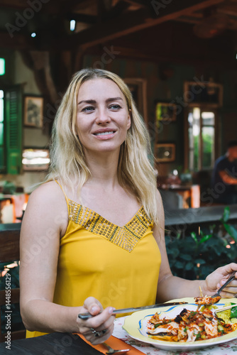 Content lady in summer top having meal in exotic restaurant