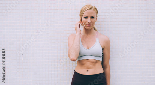 Obraz na płótnie Sportive woman in activewear standing near wall w salonie
