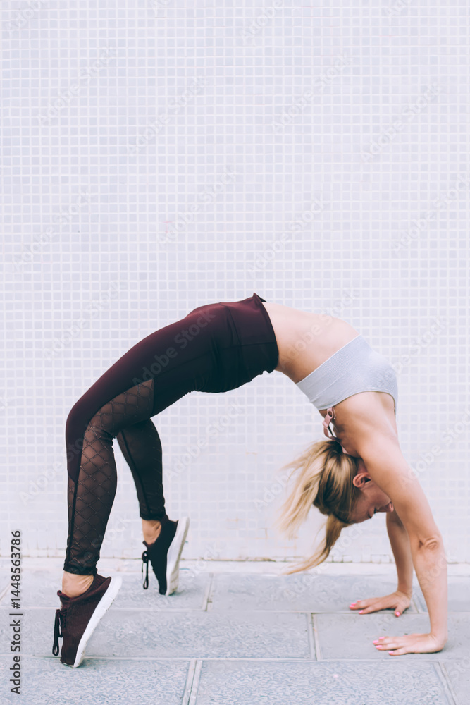 Strong sportswoman practicing yoga on street