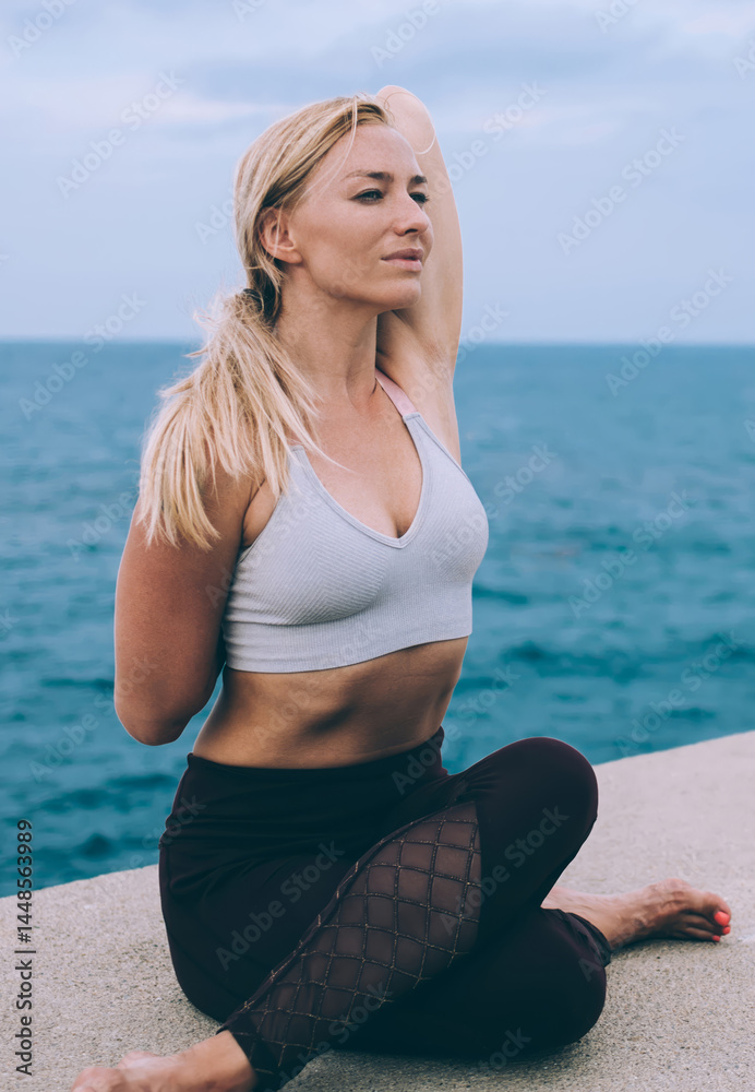 Flexible woman stretching on embankment in cloudy day