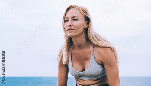 Experienced Caucasian female standing on hands doing yoga during morning workout in nature environment near coastline, Sportswoman practicing lolasana pose enjoying healthy energy lifestyle