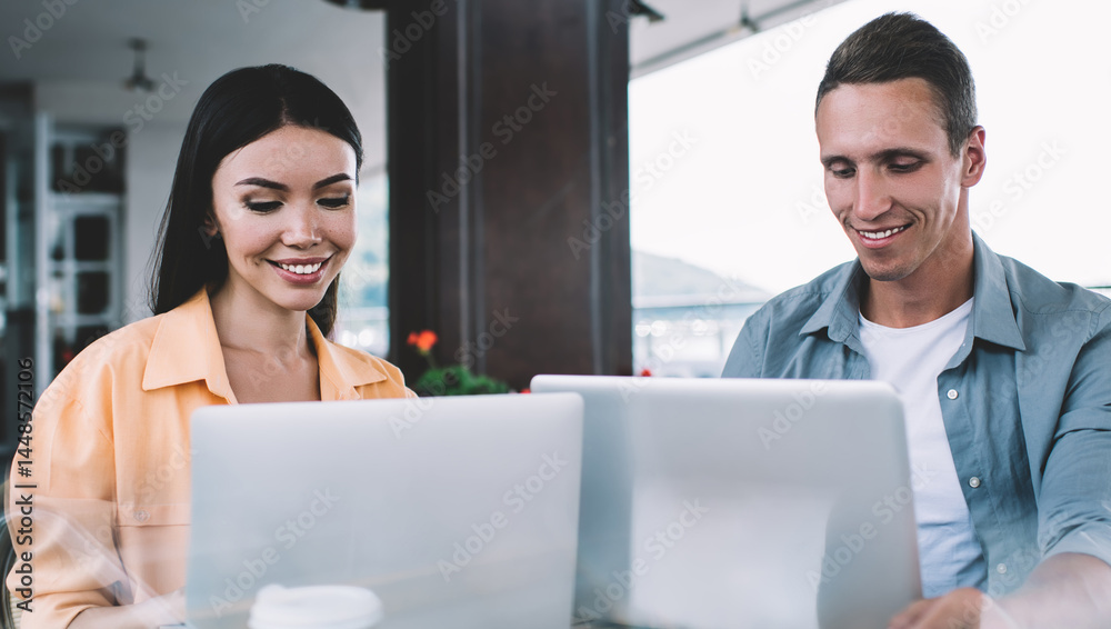 Friends working together on laptops in cafe