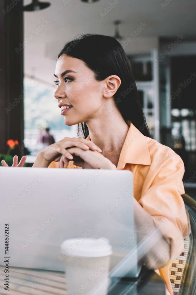 Coworkers chatting while sitting with laptops on restaurant terrace