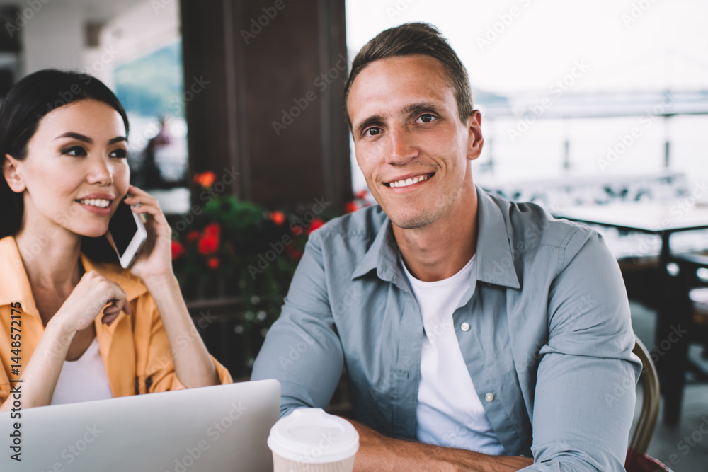 Cheerful diverse man and woman sitting in cafe with gadgets
