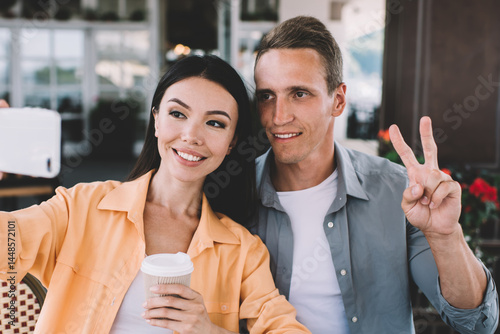 Obraz na płótnie Cheerful couple taking selfie with takeaway coffee w salonie
